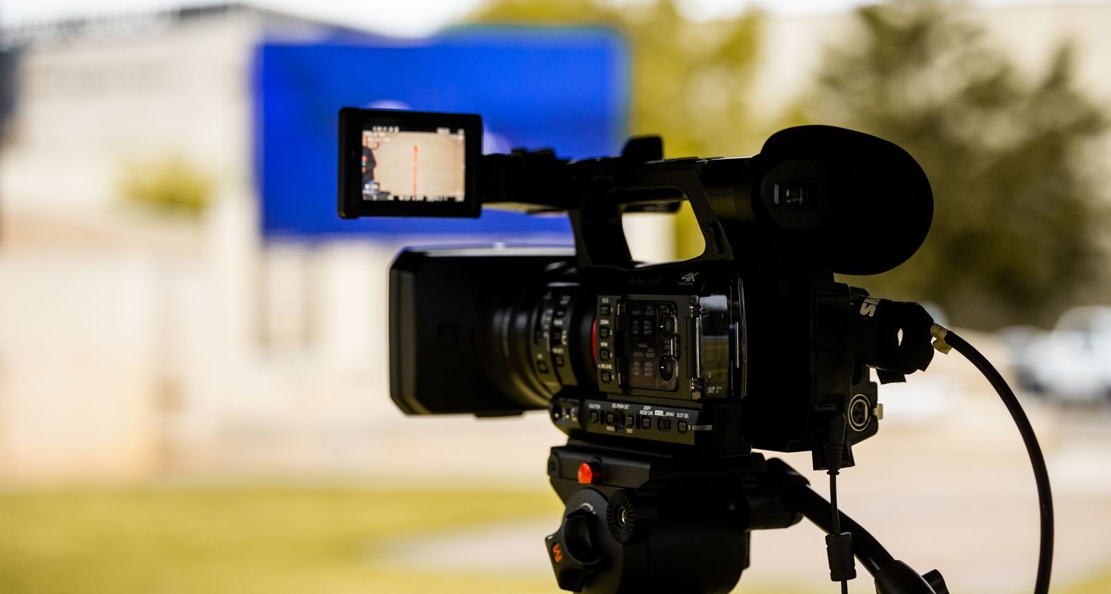 Close de uma câmera de vídeo profissional montada ao ar livre, pronta para filmar