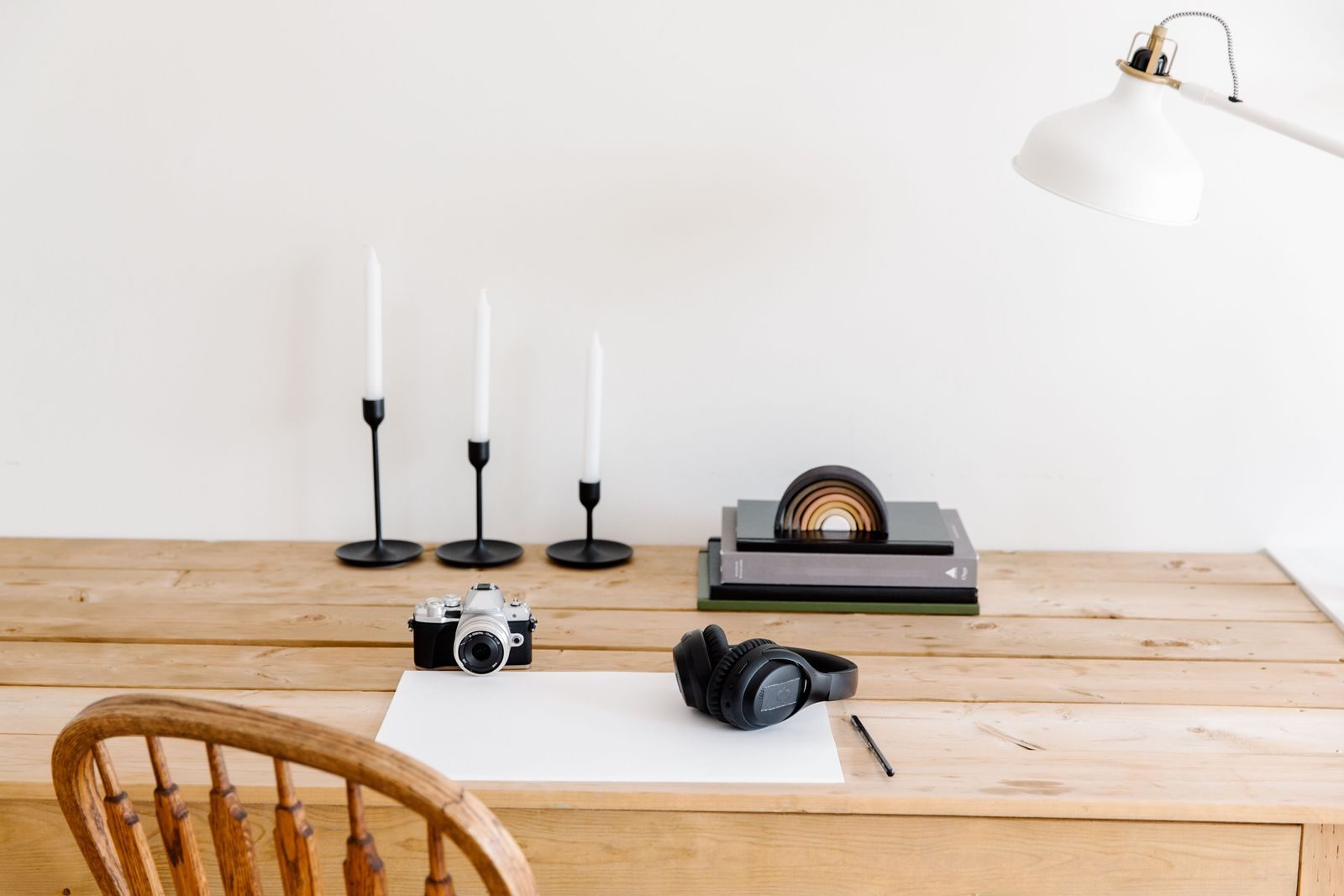 Mesa elegante e minimalista com câmera, fones de ouvido e castiçais