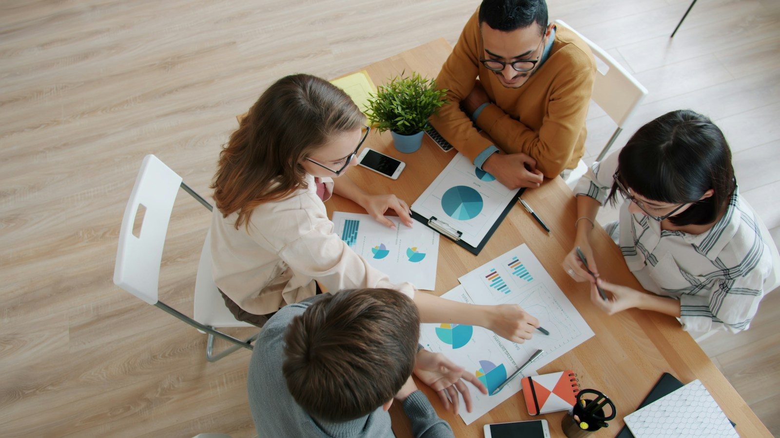 Equipe diversa colaborando em volta de uma mesa com gráficos