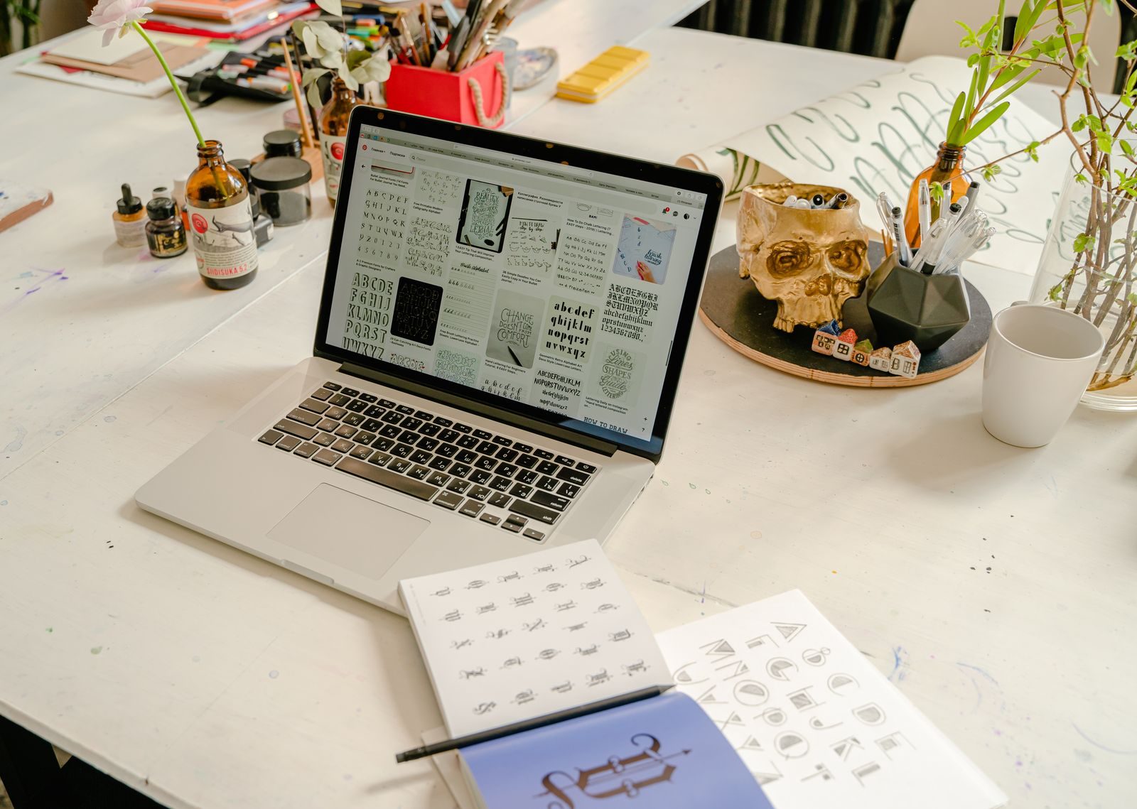 Espaço de trabalho criativo com notebook, livro de caligrafia e materiais de escrita na mesa