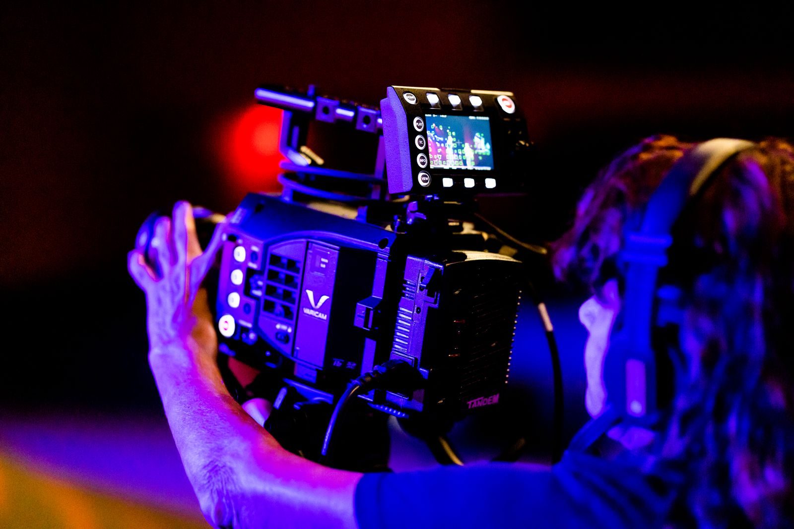 Operador de câmera trabalhando com equipamento profissional em um estúdio de TV pouco iluminado