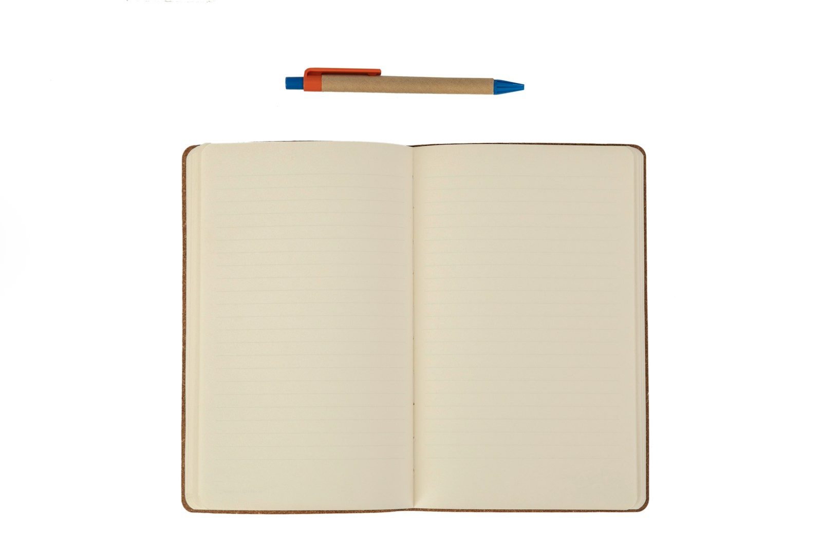 Caderno aberto com páginas pautadas e uma caneta esferográfica acima