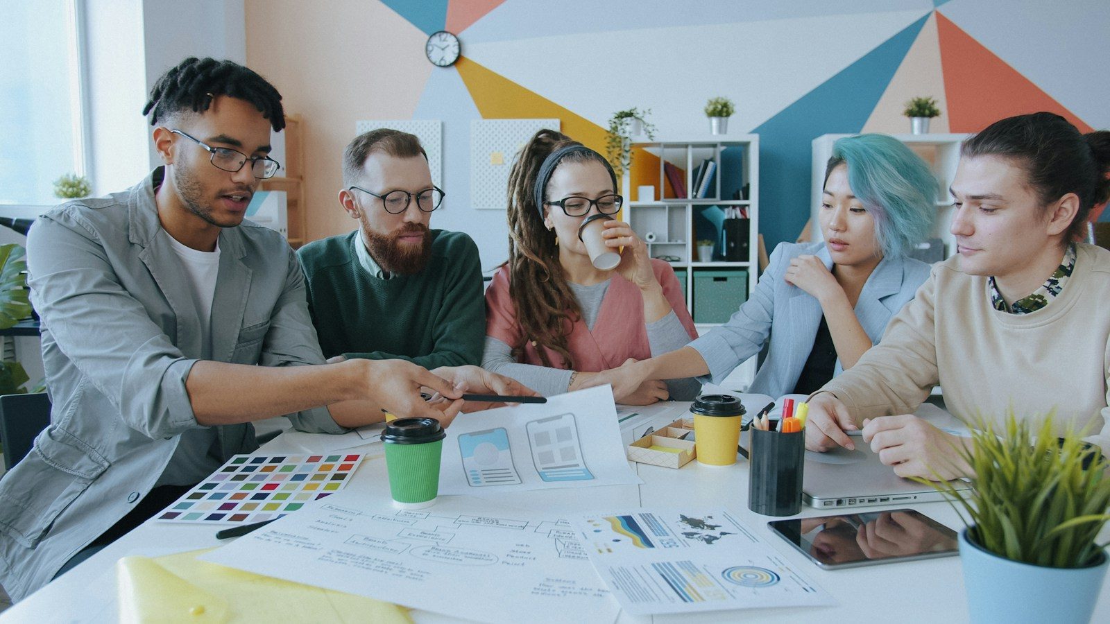 Grupo diverso de cinco pessoas colaborando em um projeto de design em um espaço de trabalho
