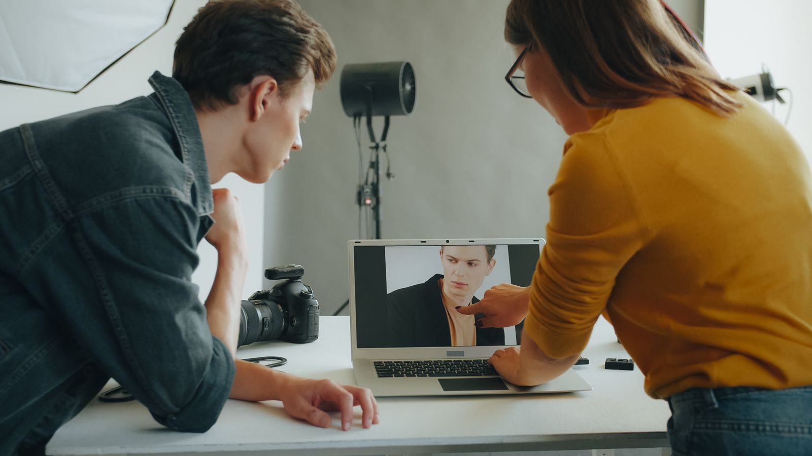 Dois fotógrafos analisam um retrato no notebook durante sessão em estúdio
