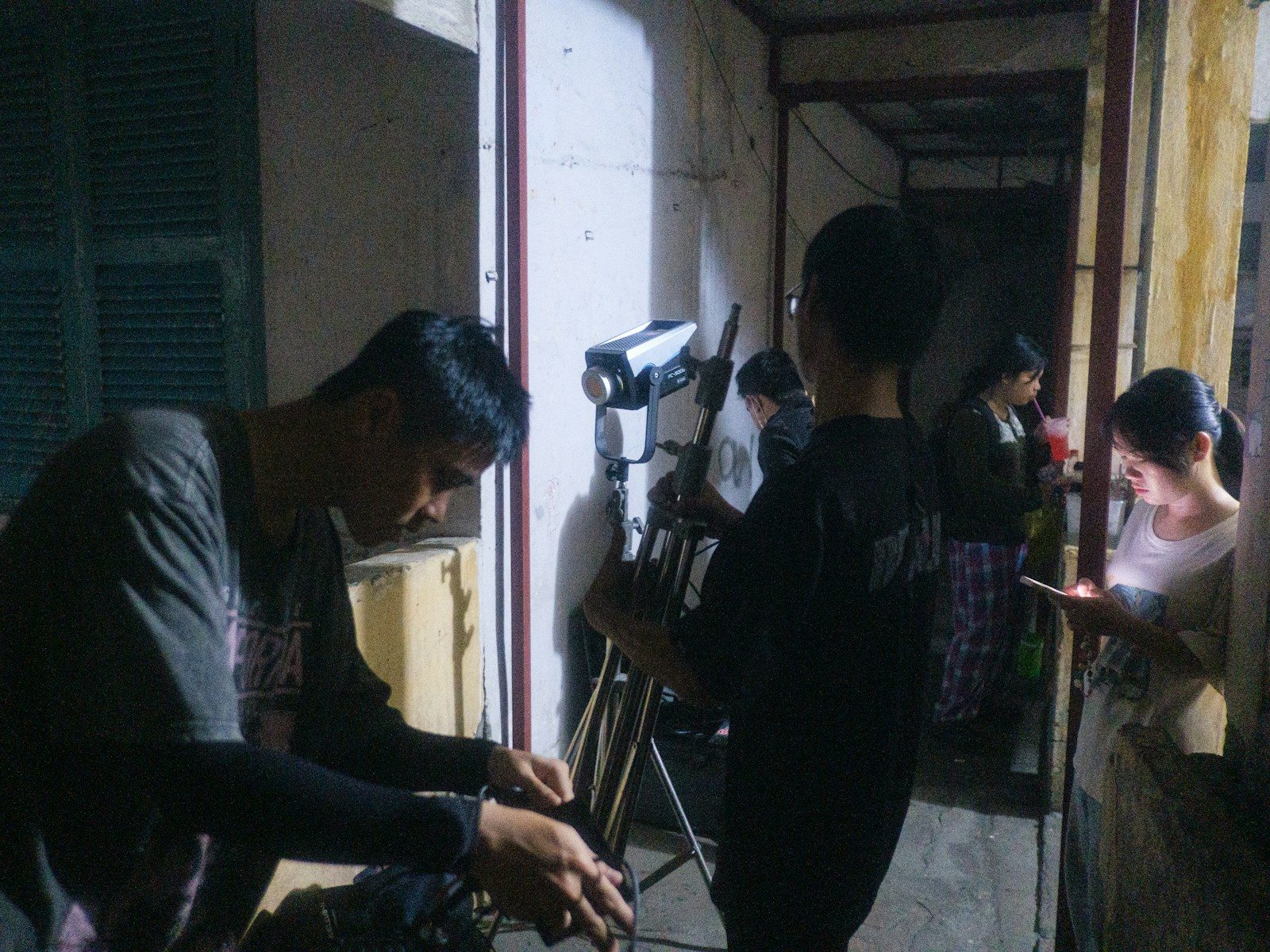 Cineastas montando equipamento de câmera em ambiente interno à noite