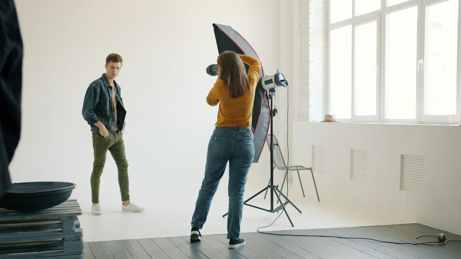 Fotógrafo orientando modelo masculino sob iluminação de estúdio