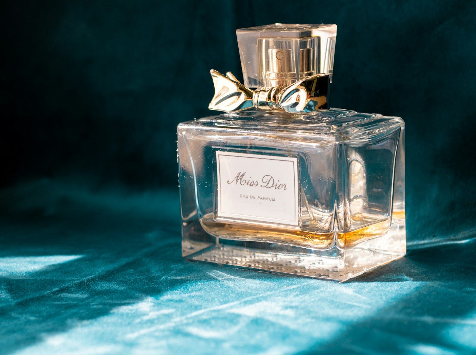 Frasco de perfume de vidro transparente sobre tecido azul