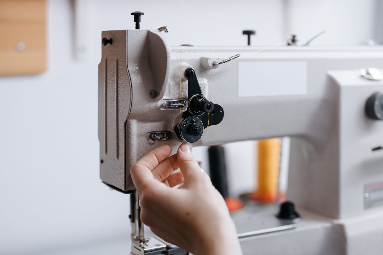 Mão operando uma máquina de costura com linha fina