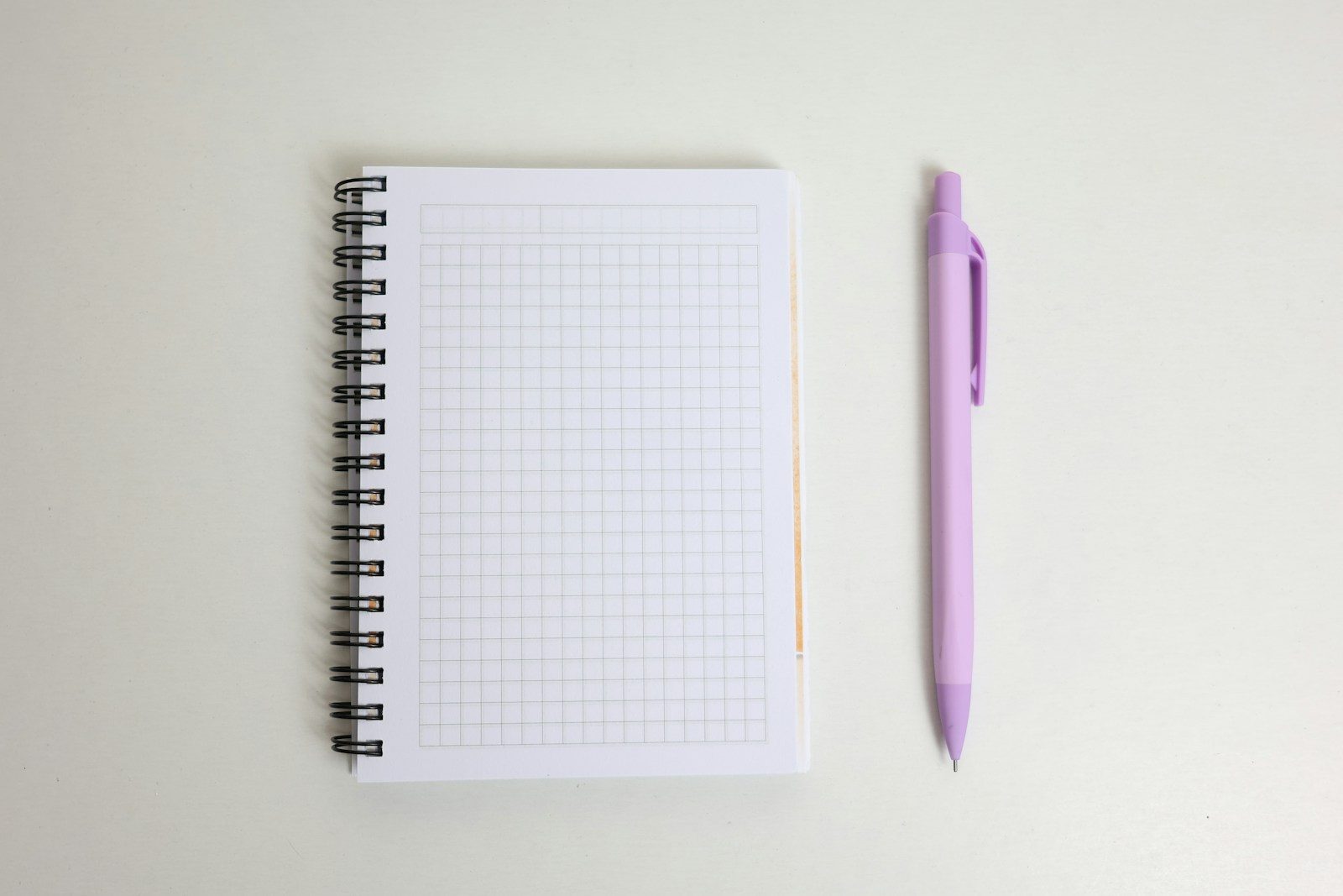 Caderno em branco e uma caneta roxa