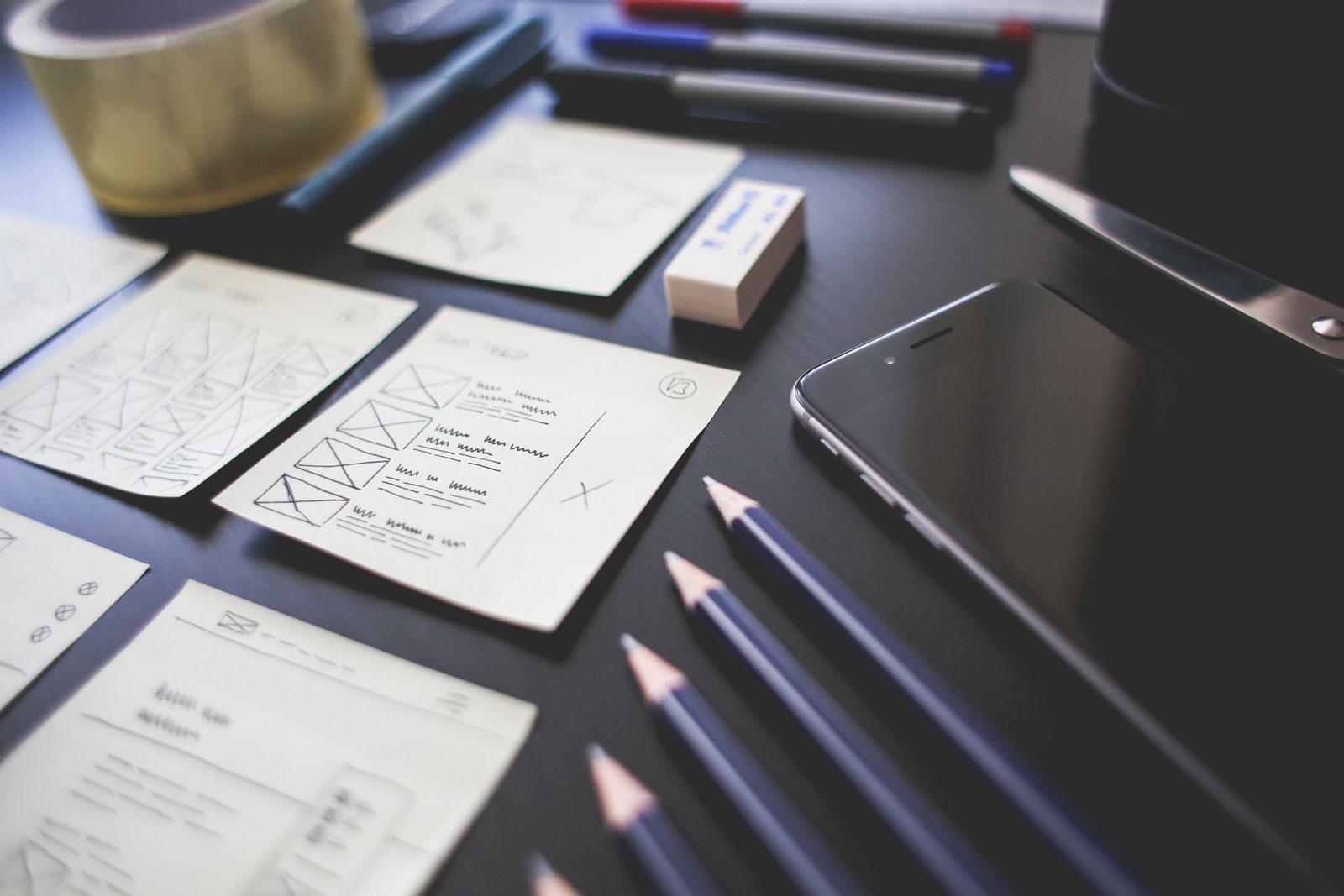 Espaço criativo com esboços de design de UI, lápis, smartphone e outros materiais de escritório