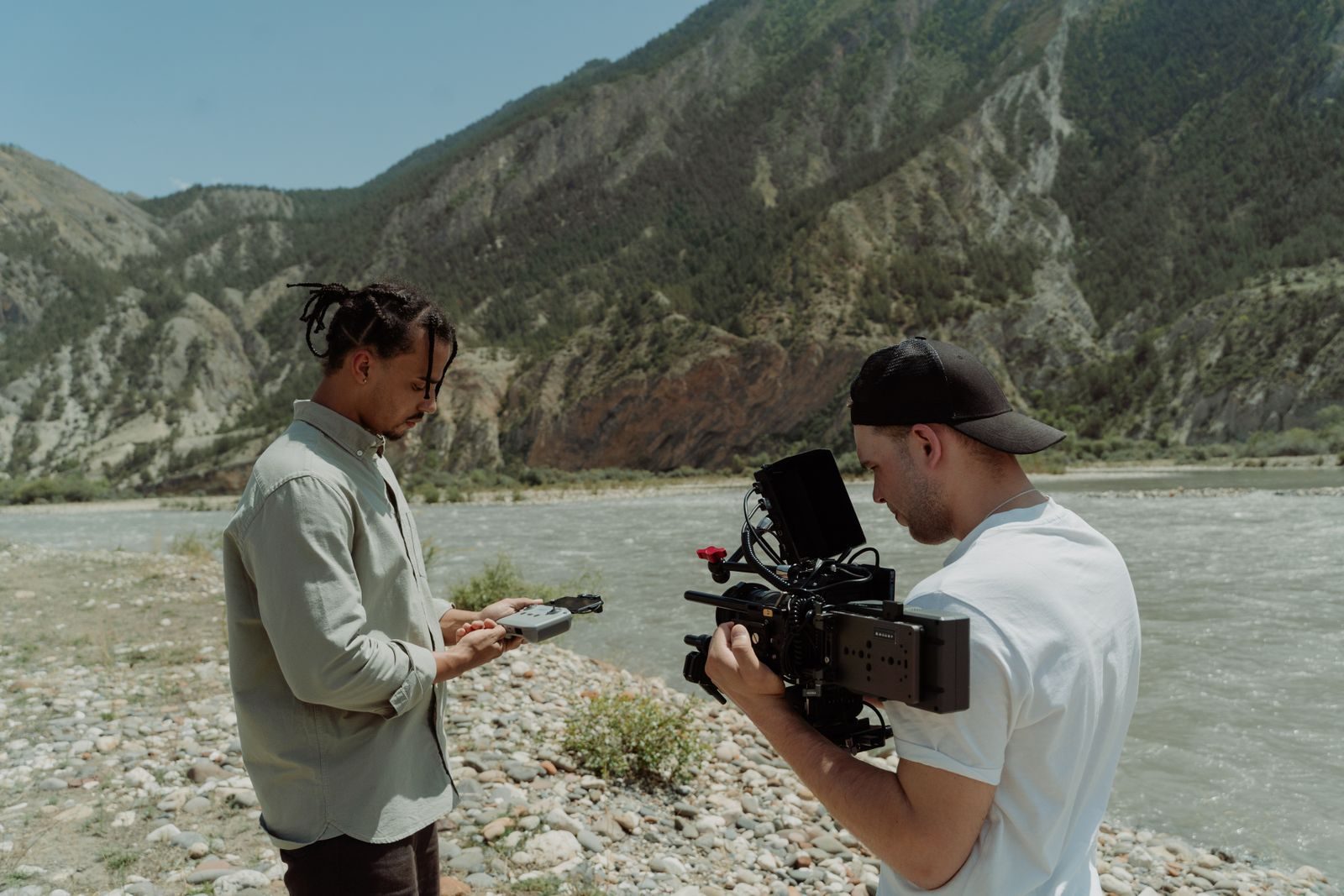 Dois cineastas filmam um rio de montanha com uma câmera profissional