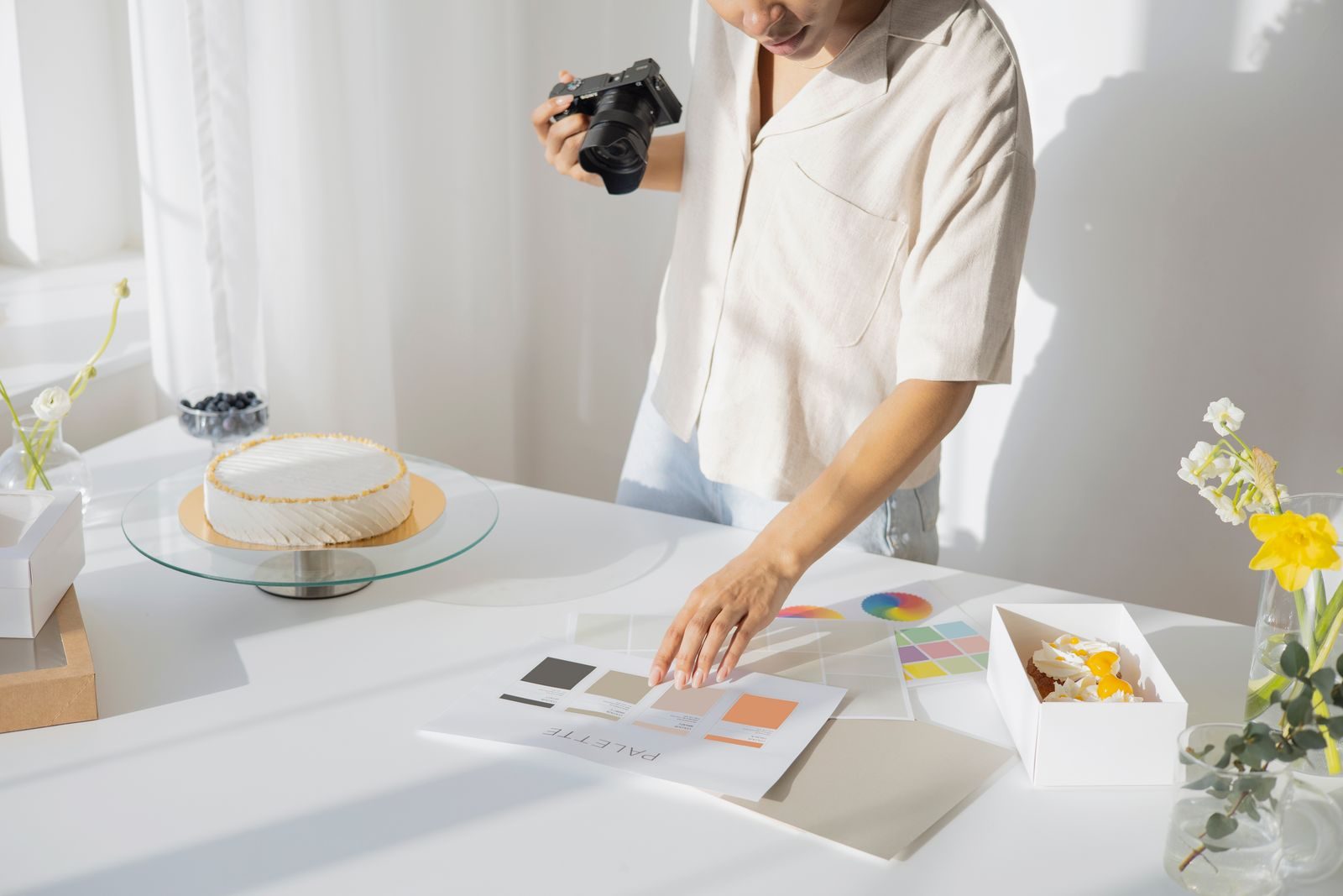 Fotógrafo organizando objetos e paletas de cores em um estúdio claro para foto de produto
