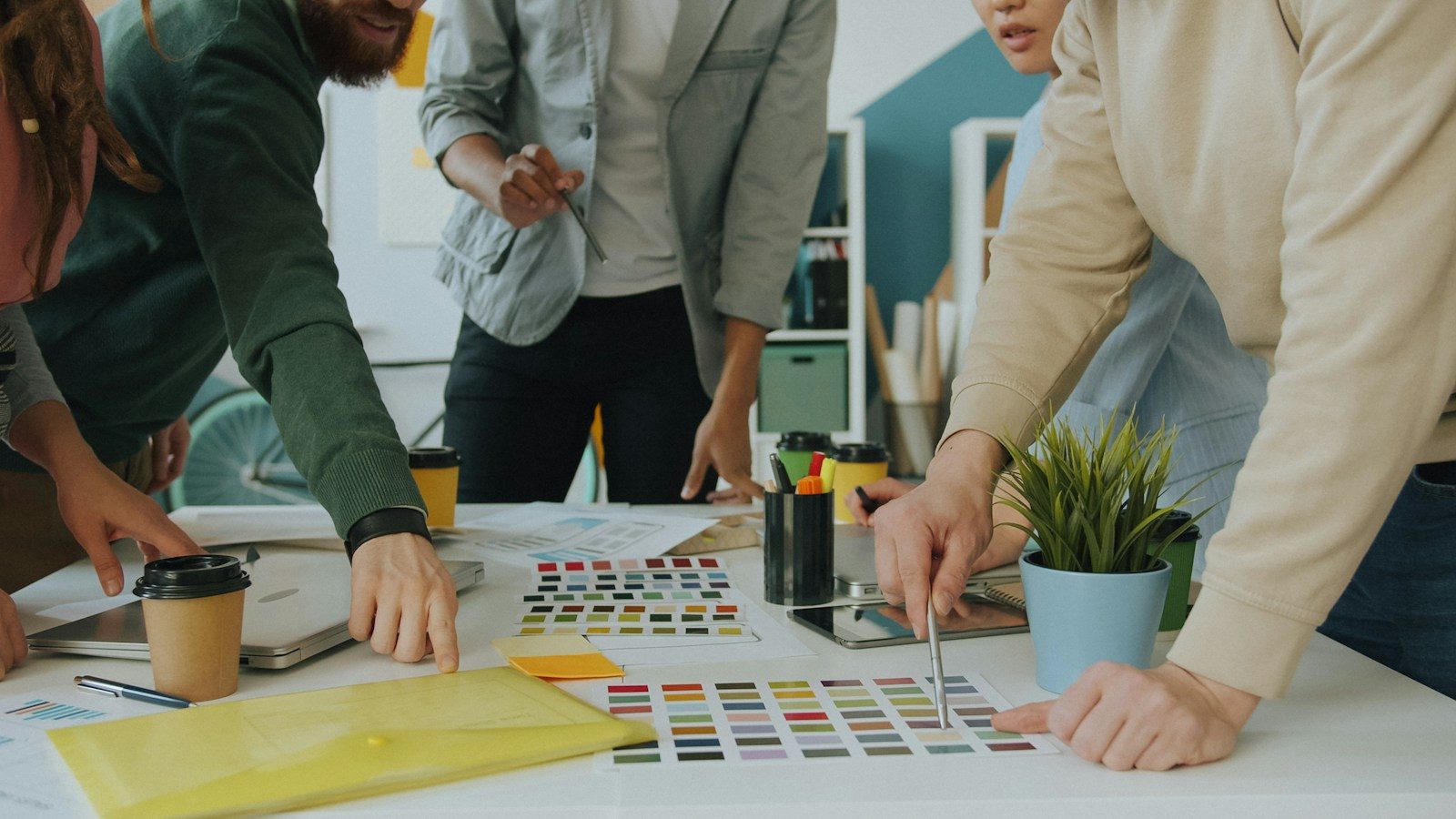 Grupo de pessoas colaborando em um projeto de design em uma mesa branca