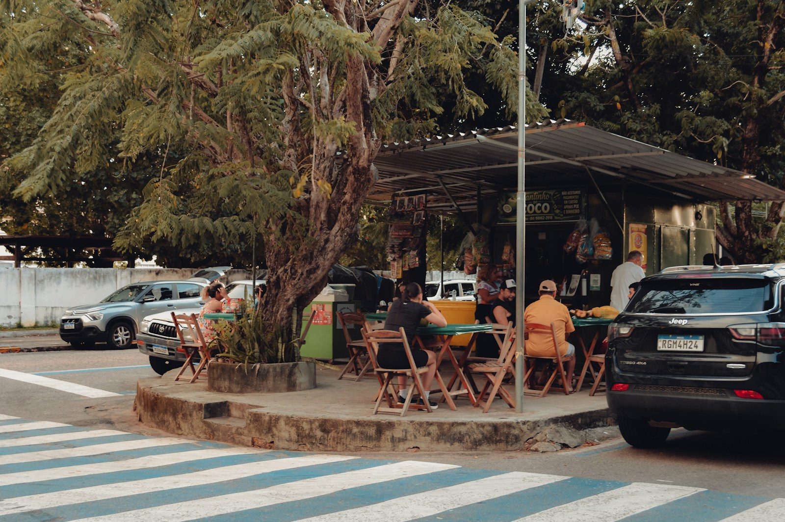 Pessoas aproveitando um café ao ar livre em esquina sombreada