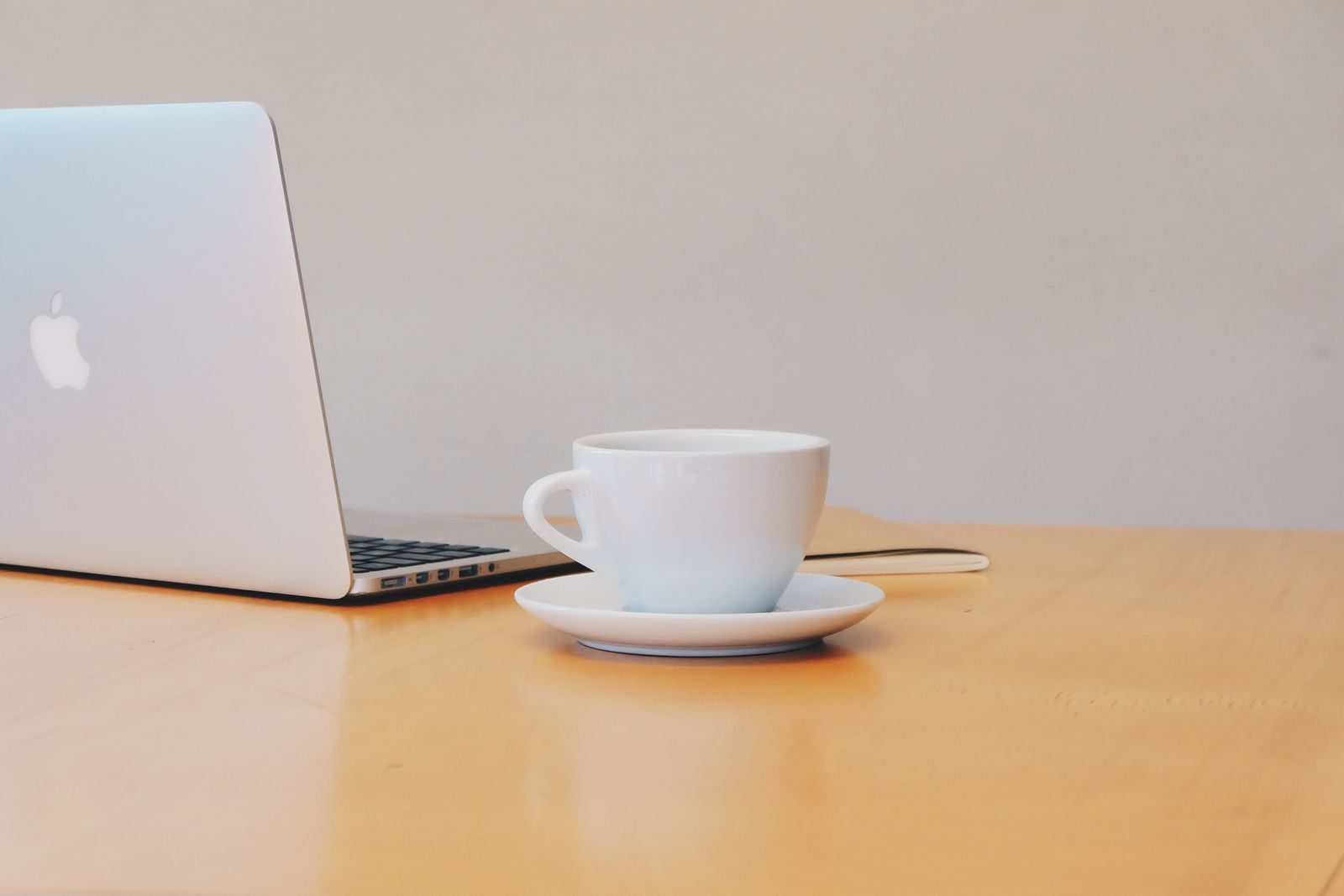 Espaço de trabalho limpo e moderno com notebook e xícara de café branca em mesa de madeira