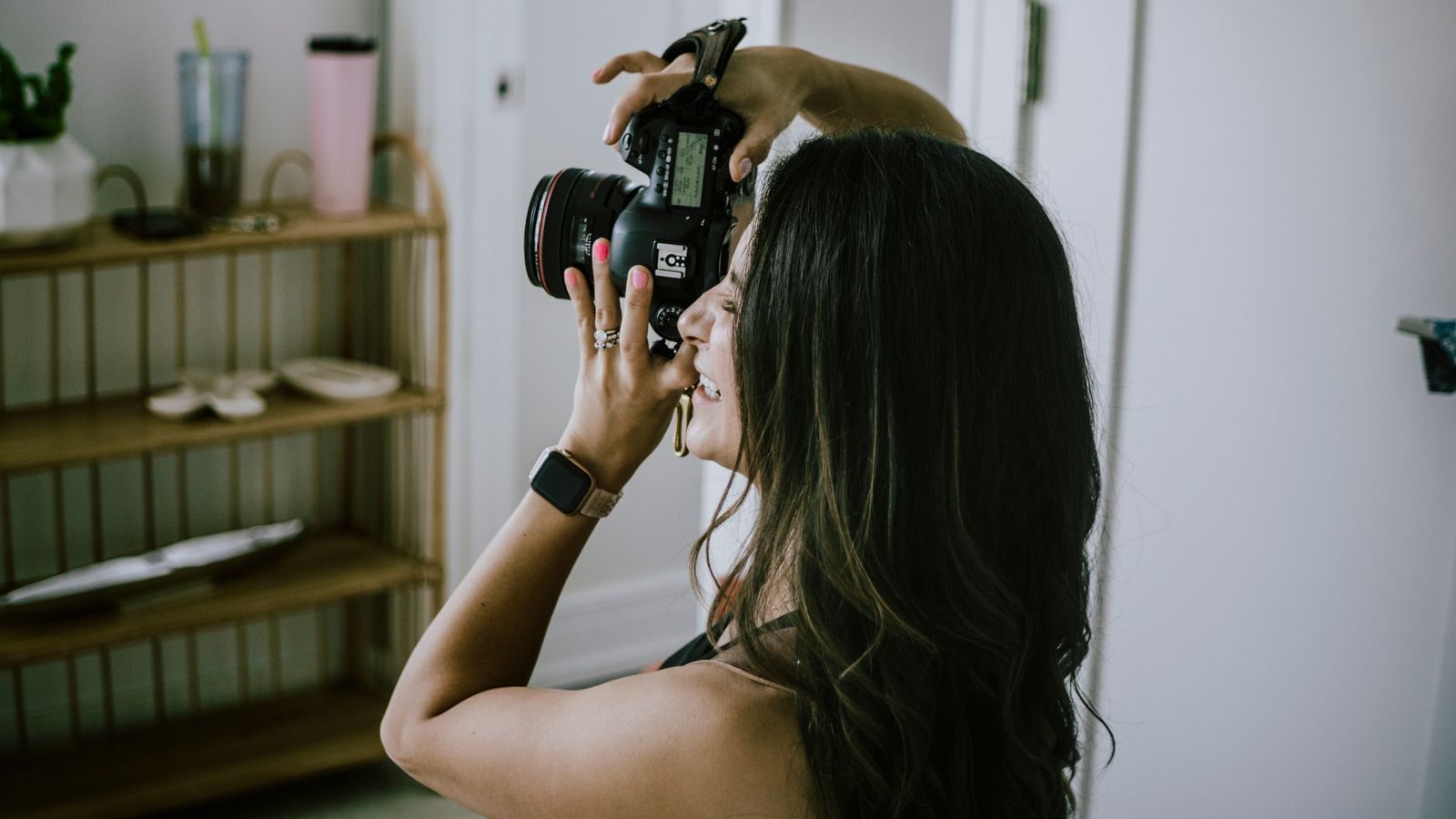 Mulher tirando foto com uma câmera DSLR em ambiente interno