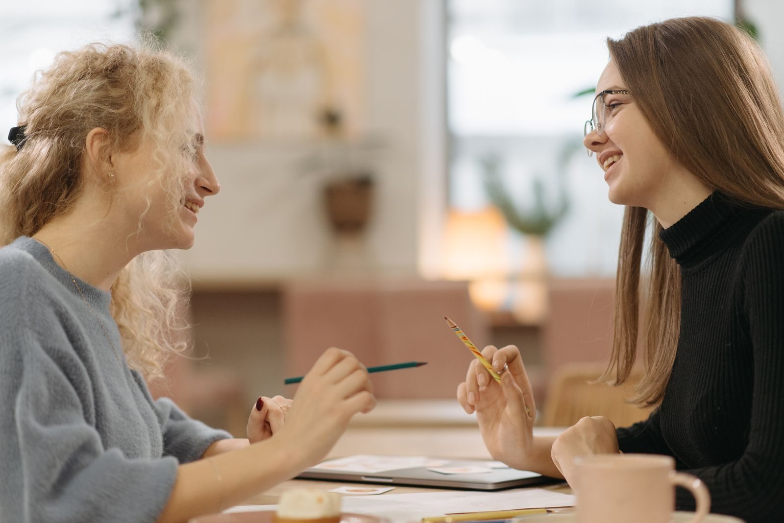 Duas jovens sorrindo e conversando em ambiente interno acolhedor