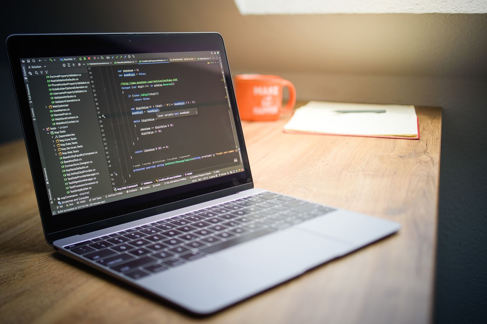 Notebook exibindo código em uma mesa com caderno e caneca em espaço de trabalho moderno