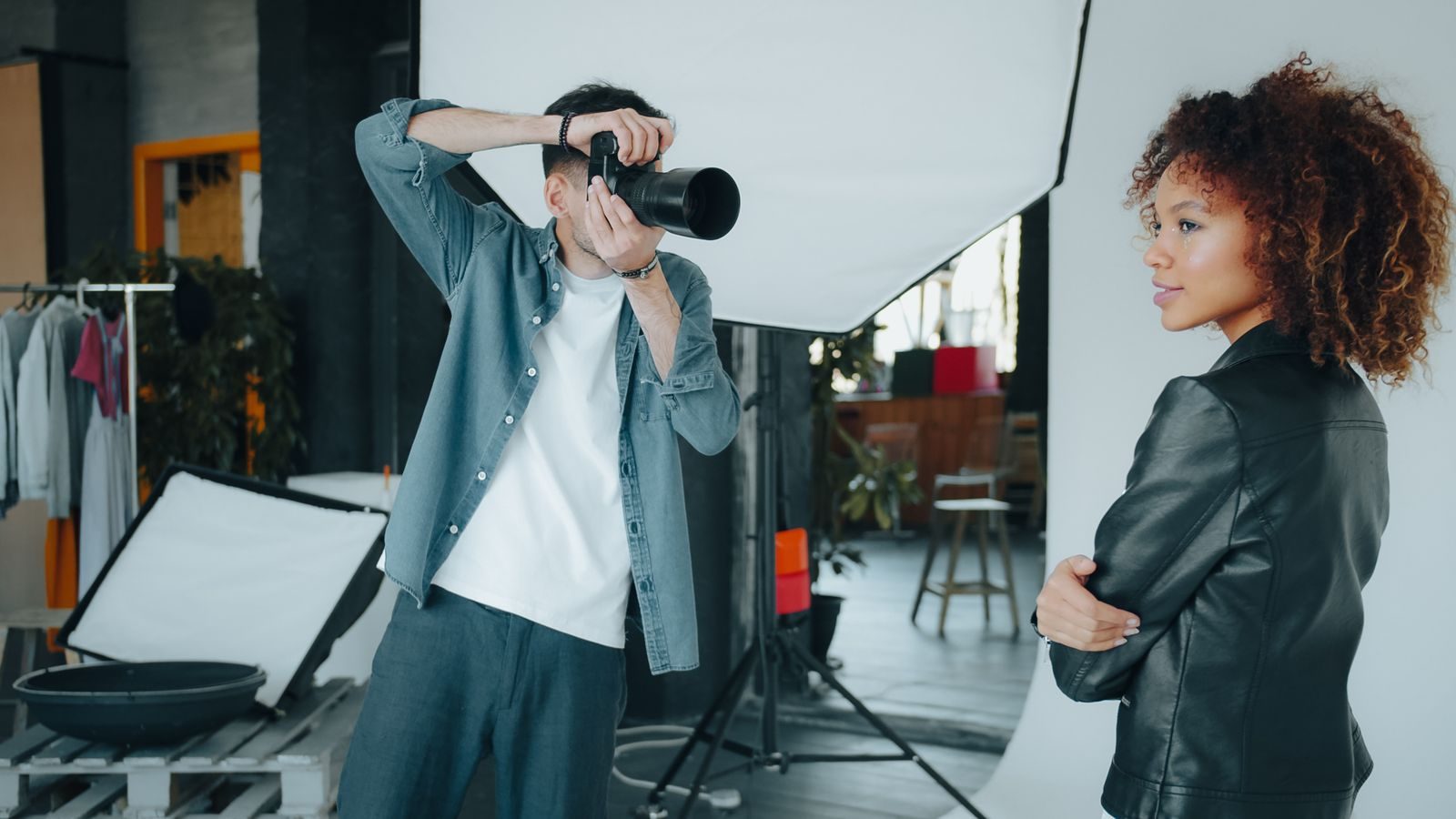 Fotógrafo clicando modelo em estúdio moderno com equipamento profissional