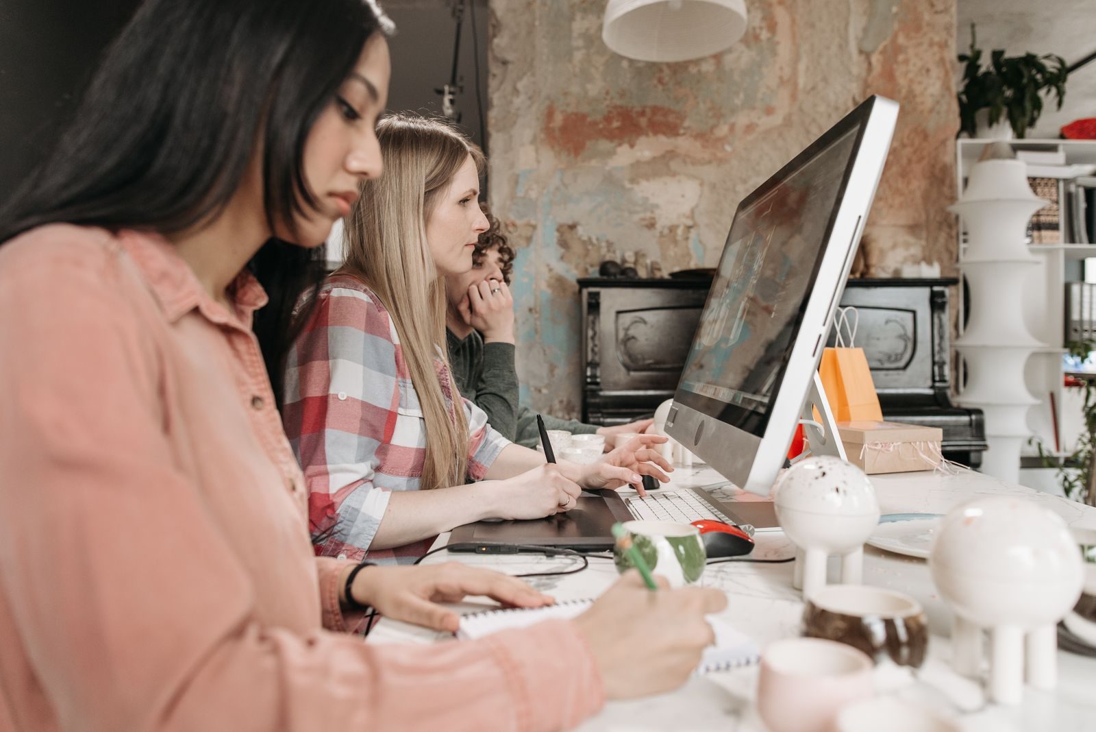 Três jovens profissionais colaboram usando tecnologia em um escritório elegante