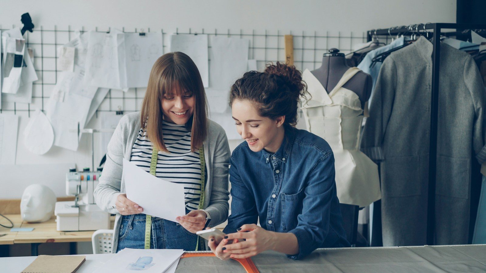 Dois designers colaborando e revisando projetos sorridentes