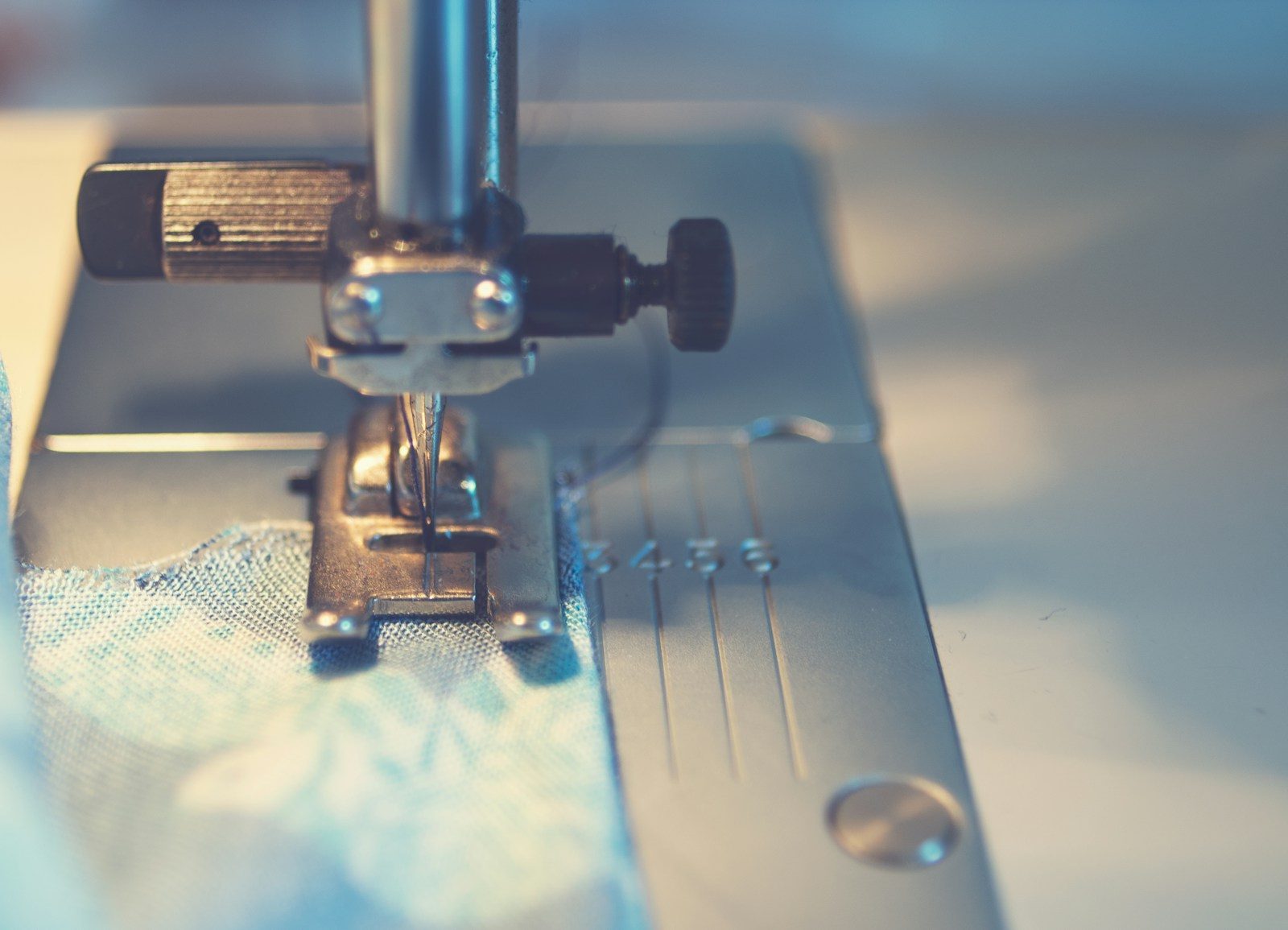 Tecido azul sob a agulha de uma máquina de costura