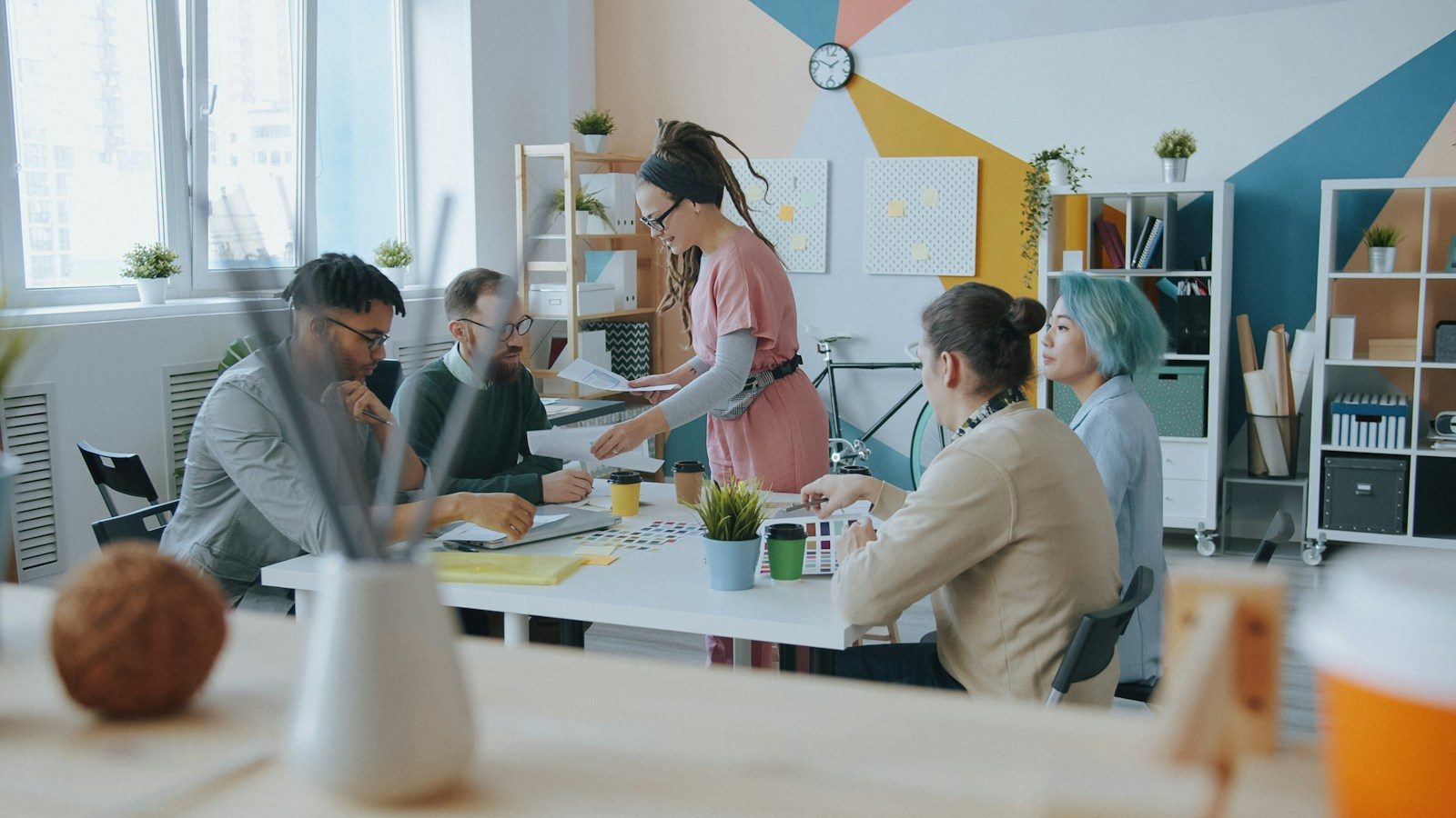 Grupo diverso de pessoas colaborando em uma mesa em um escritório colorido