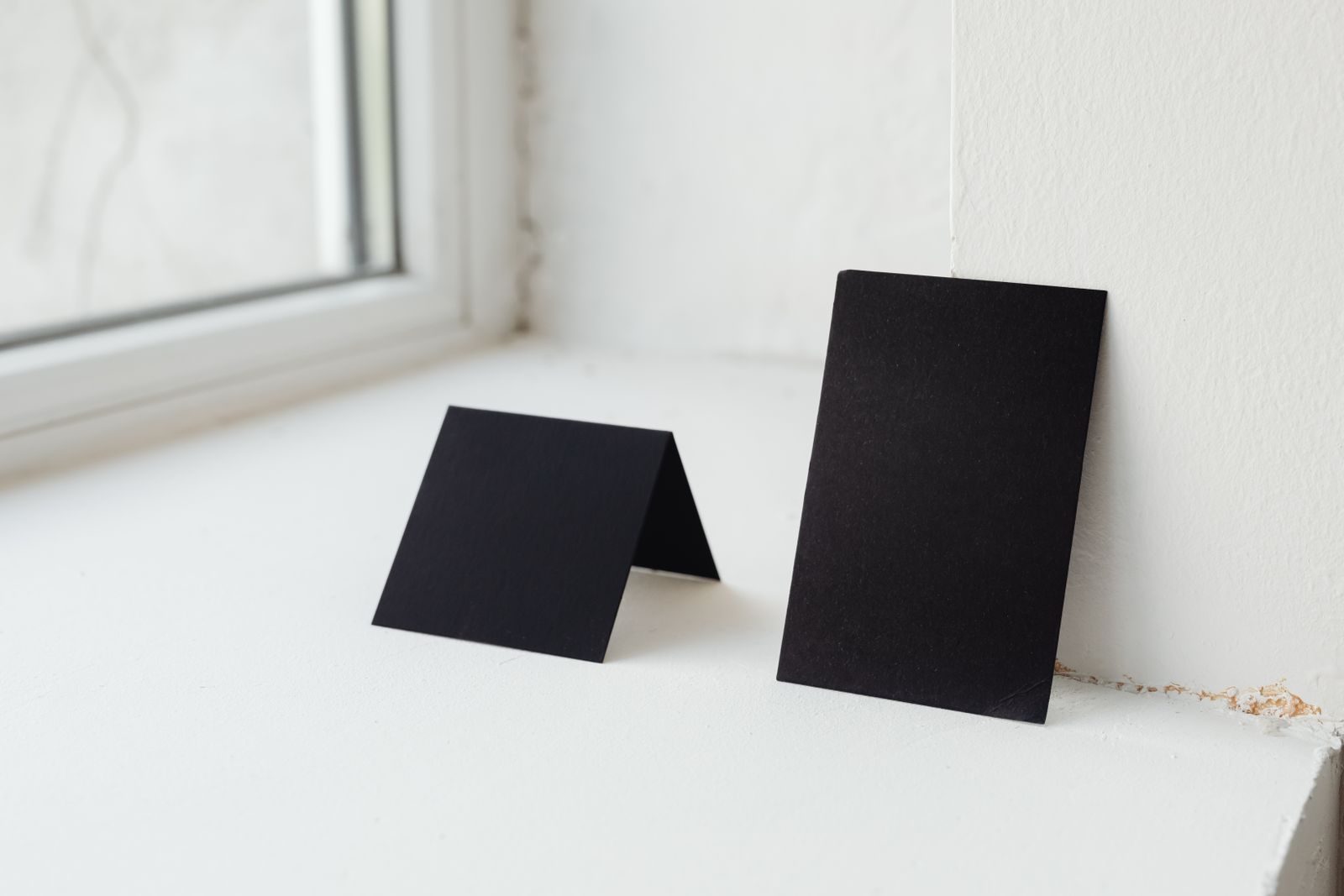 Dois cartões pretos sobre um parapeito branco, ideais para mockups e apresentações
