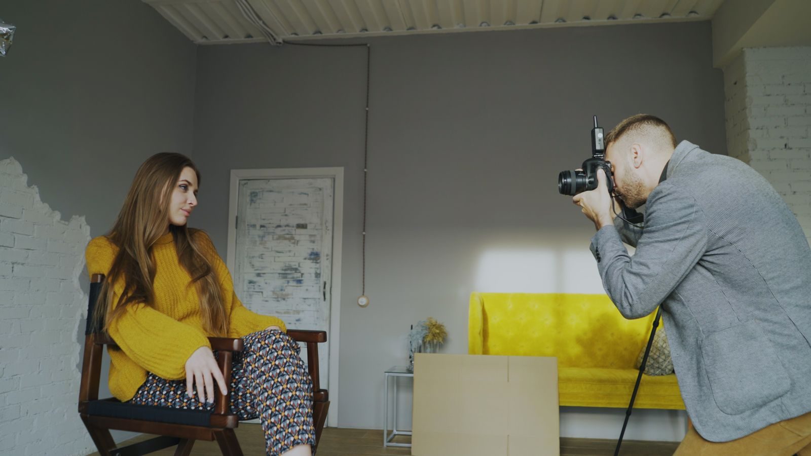 Fotógrafo fotografando mulher sentada durante sessão em estúdio