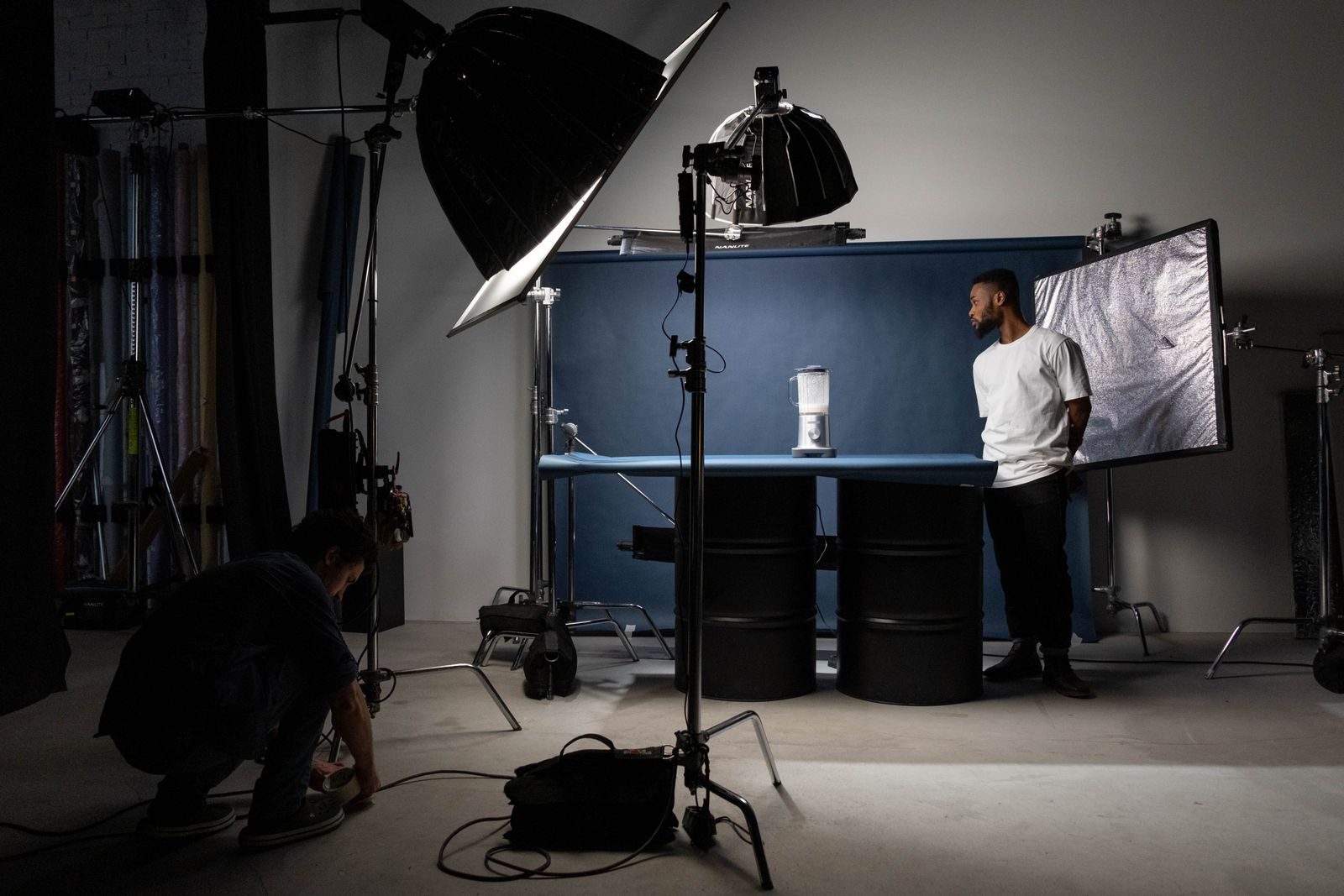 Estúdio com equipamentos de iluminação, modelo e equipe durante sessão de fotos