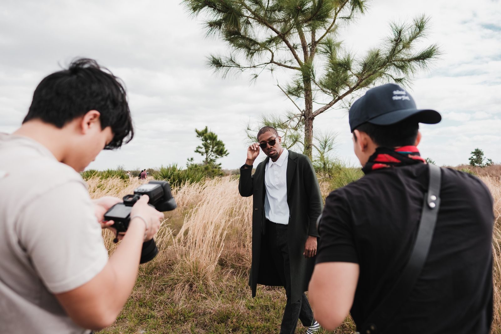 Ensaio de moda ao ar livre com modelo posando para fotógrafos em campo gramado