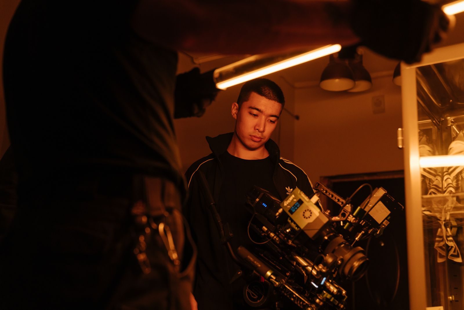 Membro da equipe de filmagem ajustando a câmera sob luz neon em ambiente interno