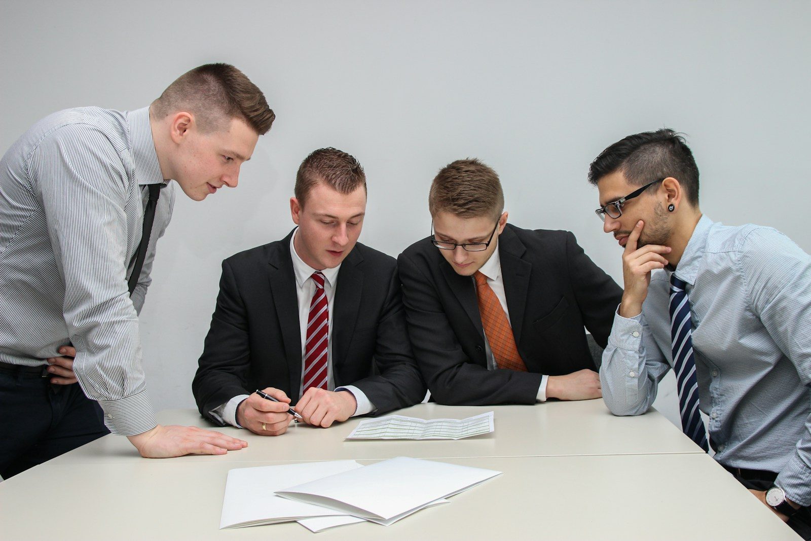 Quatro homens olhando para um papel sobre a mesa