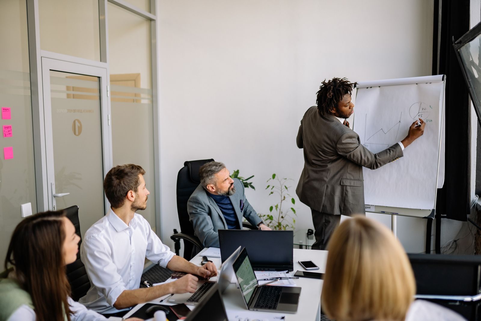 Equipe diversa em reunião estratégica conduzida por um apresentador em escritório moderno