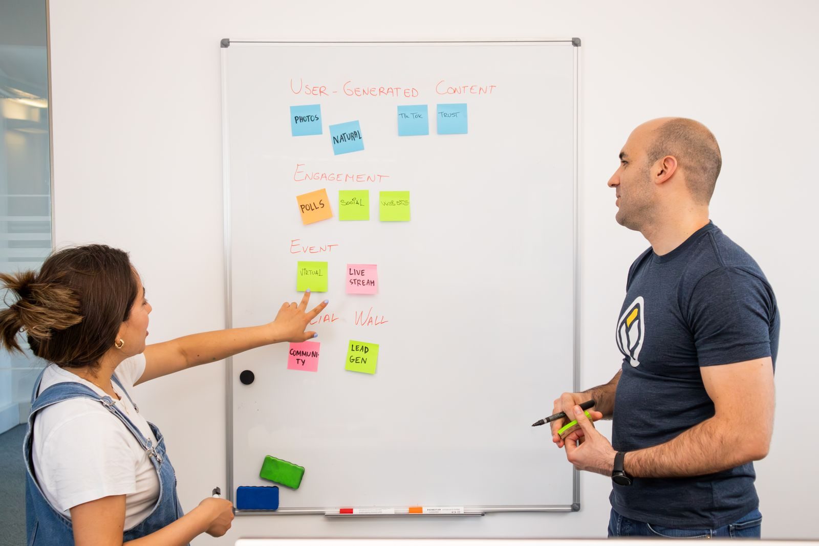 Dois profissionais fazendo brainstorming e planejando projetos em quadro branco em escritório colaborativo