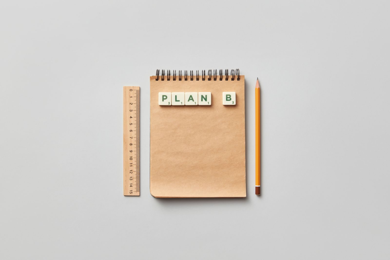 Flat lay minimalista de bloco de notas, régua e lápis com peças formando Plan B