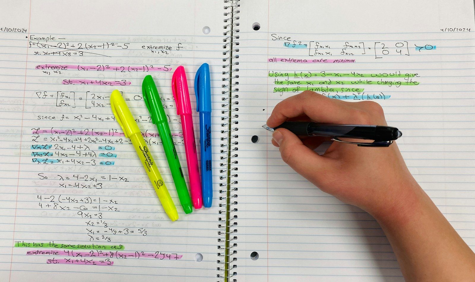 Pessoa escrevendo em um caderno com canetas coloridas