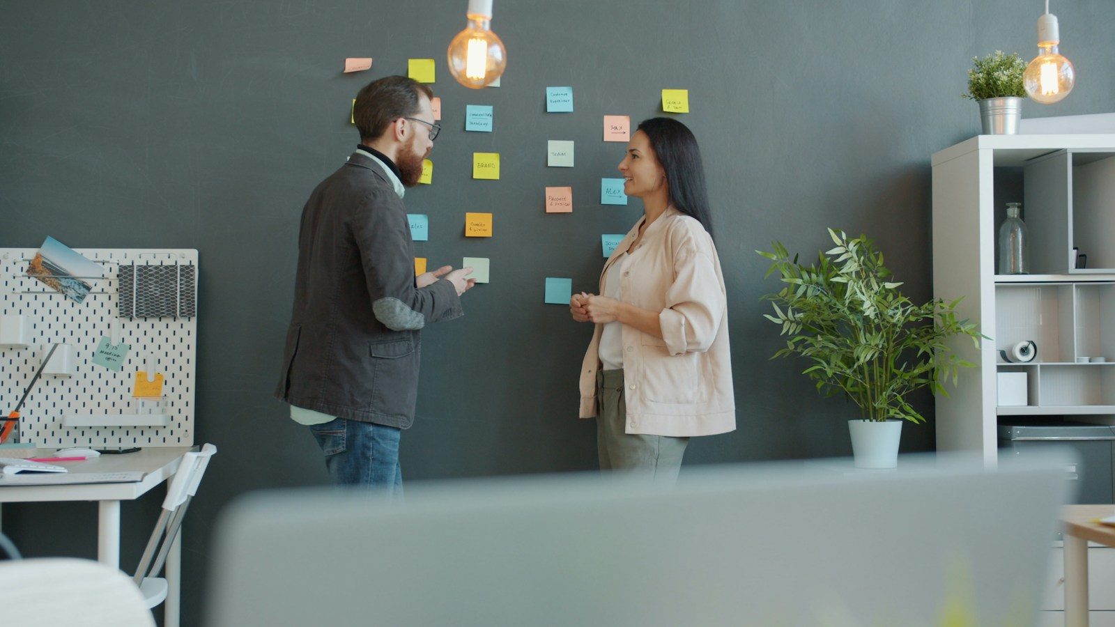 Dois colegas fazendo brainstorming com post-its na parede