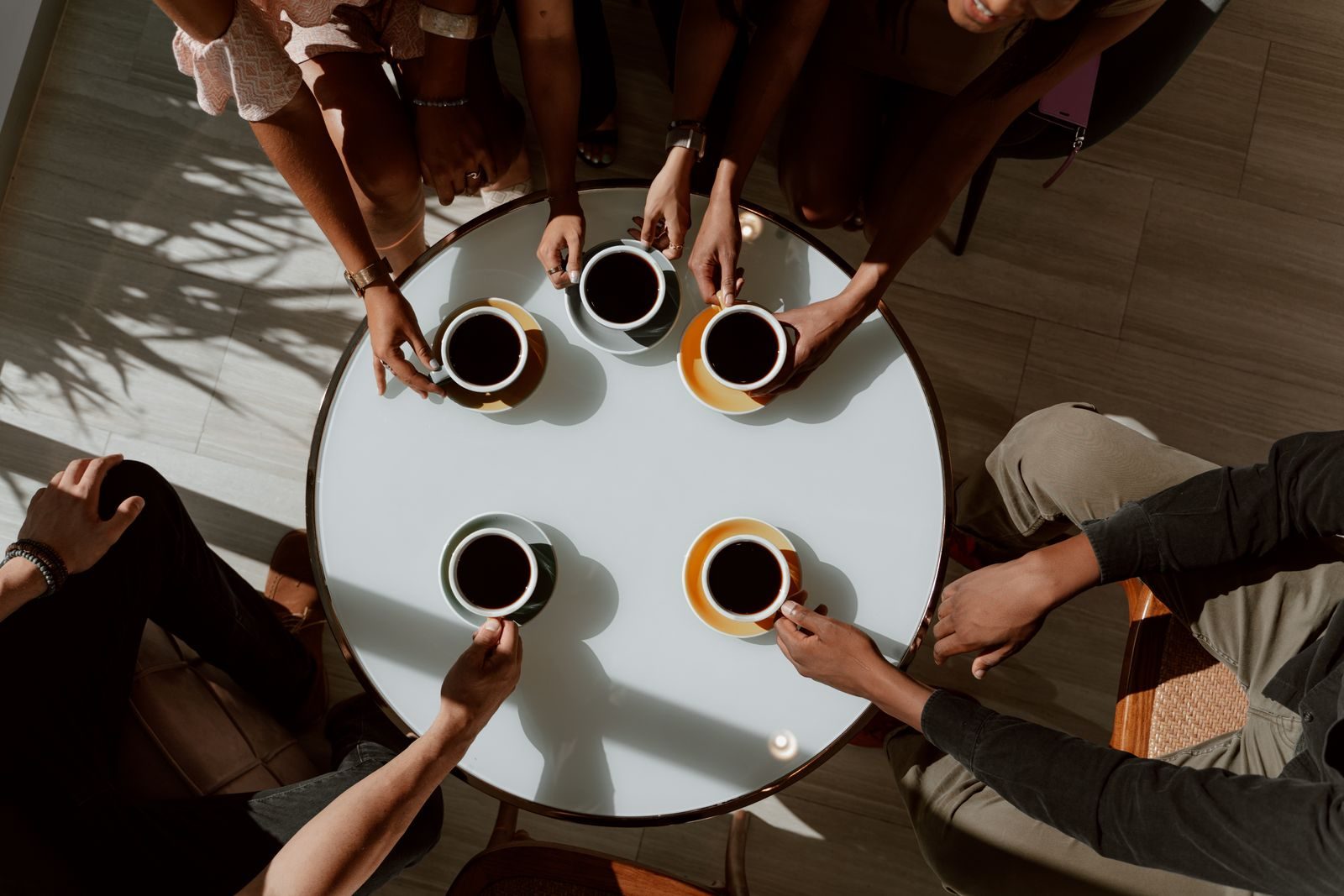 Grupo de amigos tomando café ao redor de uma mesa em ambiente acolhedor