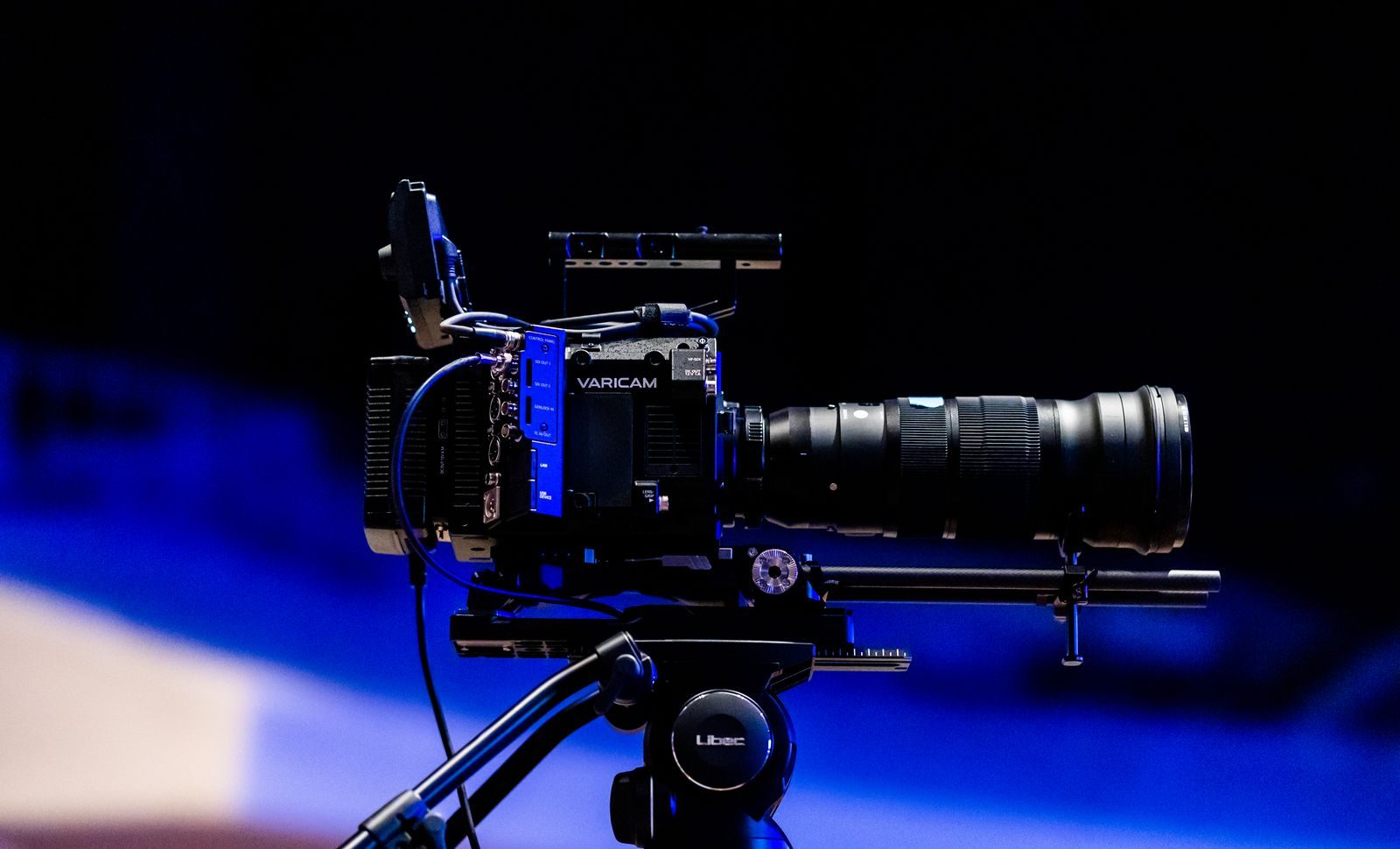 Vista lateral de uma câmera de vídeo profissional com lente em um tripé, pronta para filmar