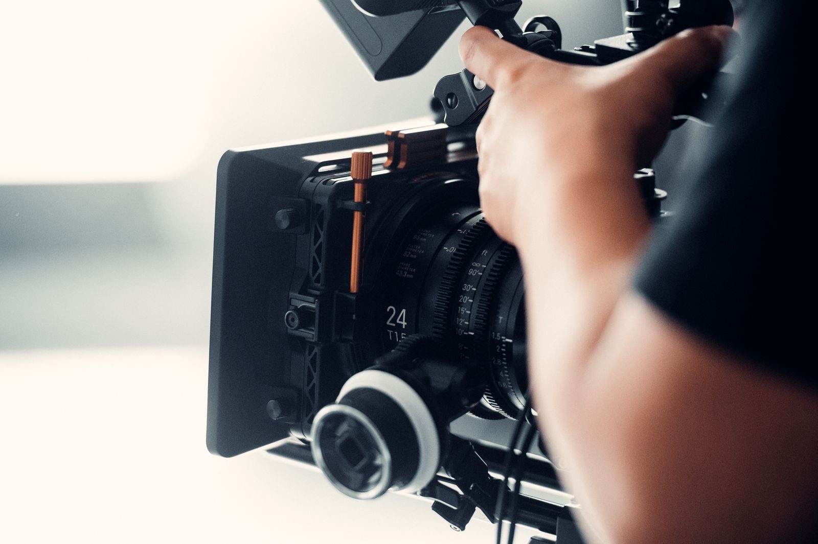 Pessoa operando uma câmera de vídeo profissional durante uma filmagem em ambiente interno