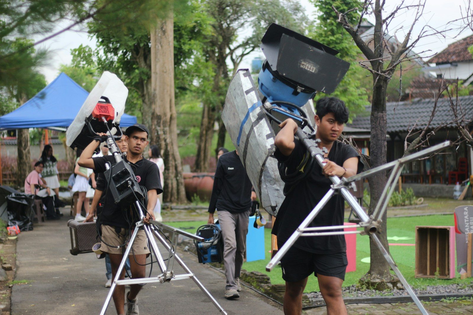 Membros da equipe carregando equipamento de filmagem ao ar livre