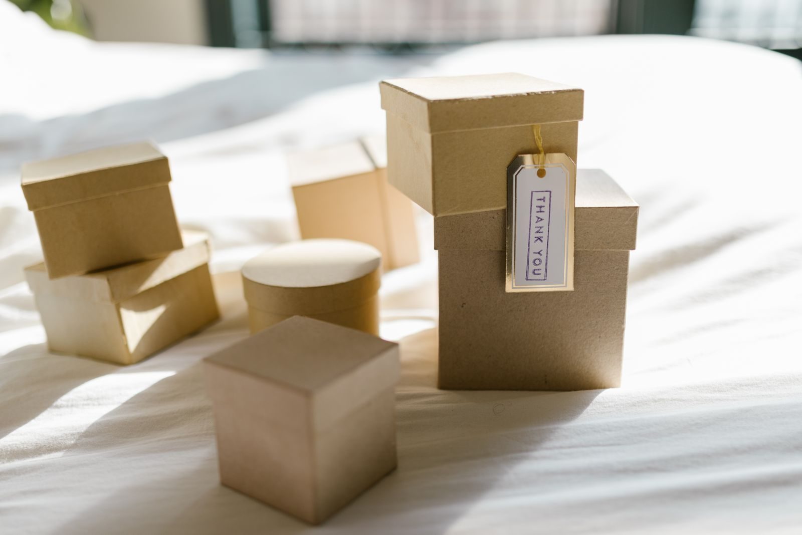 Caixas de presente de papelão em uma cama com etiqueta de agradecimento sob luz natural