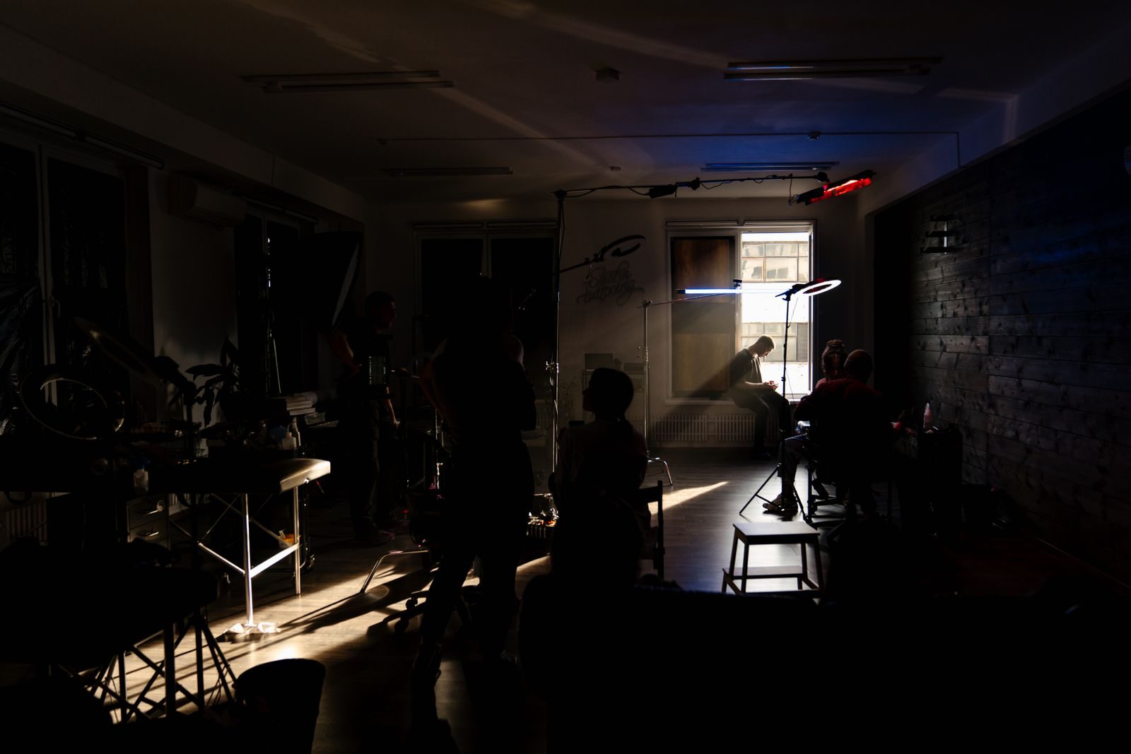Set de filmagem à meia-luz com equipe trabalhando sob luzes neon, em clima artístico