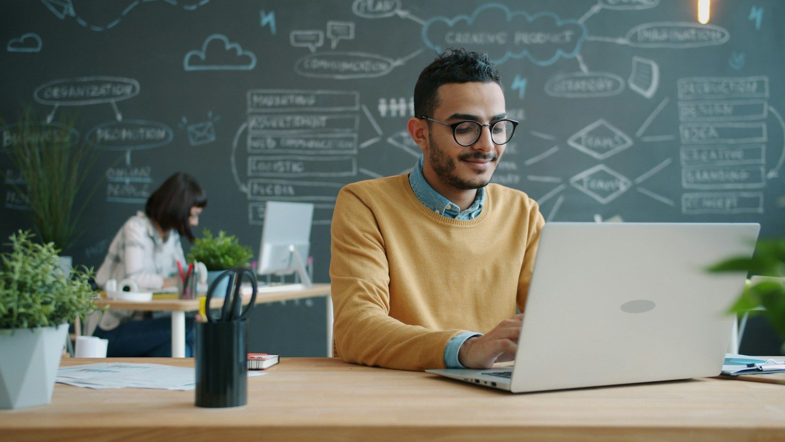 Homem trabalhando no notebook em escritório moderno com quadro branco