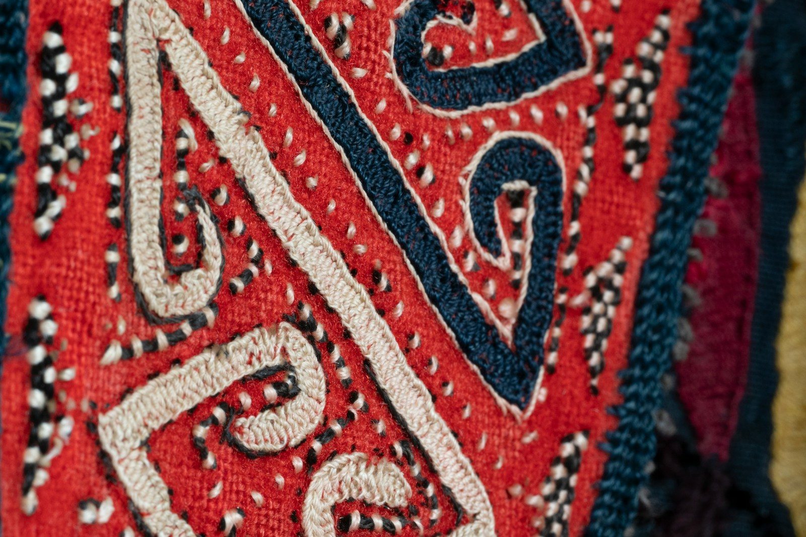 Close de tecido vermelho com estampas detalhadas em branco e azul
