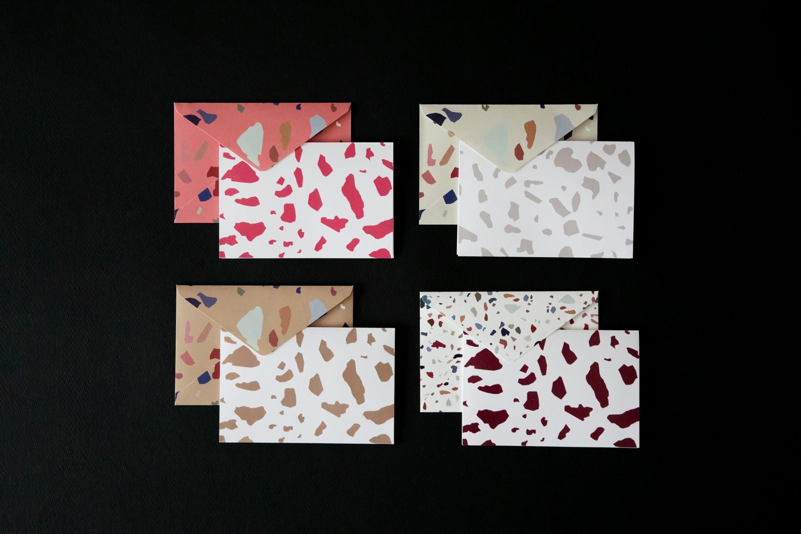 Envelopes com estampa terrazzo organizados sobre superfície preta