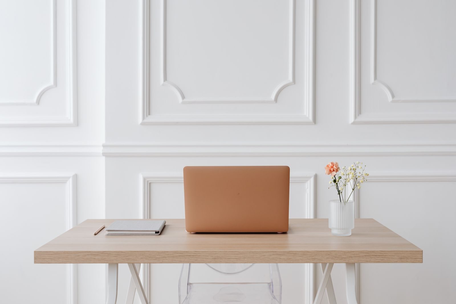 Espaço de trabalho tranquilo com mesa simples, notebook, caderno e um vaso de flores