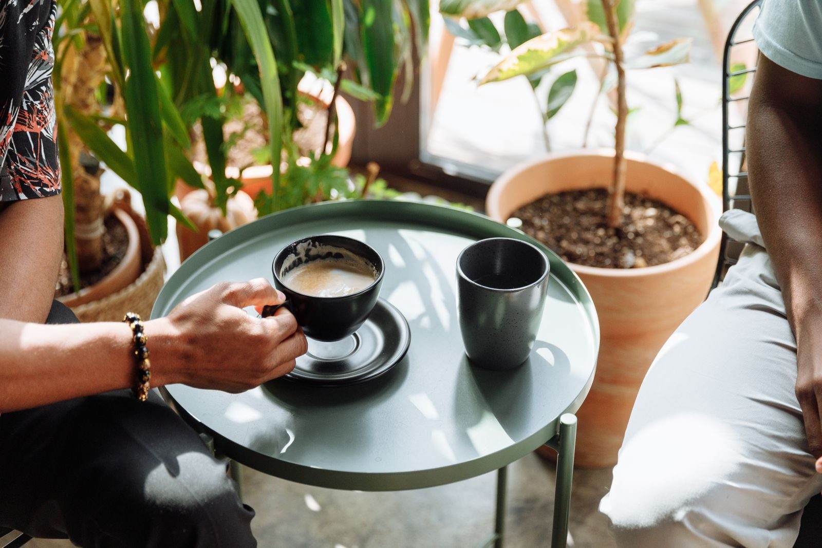 Ambiente interno aconchegante com xícara de café em uma mesa entre plantas verdes