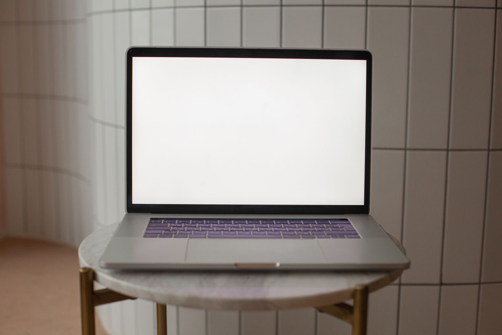 Notebook com tela em branco sobre uma pequena mesa redonda, ideal para mockup